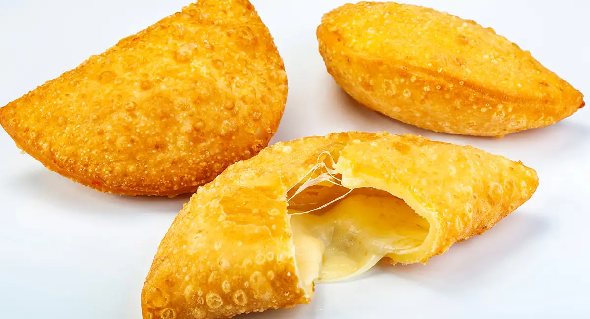 Empanada de queso boliviana con masa dorada, partida muestra queso criollo fundido por dentro.